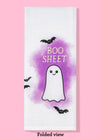 Folded view of the Boo Sheet dishtowel featuring illustrations of a cute ghost, flying bats, and a purple background.