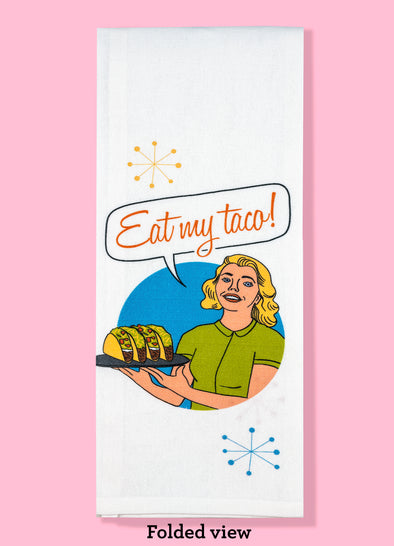 Folded dishtowel with an illustration of a woman holding a plate of tacos and the text Eat My Taco.