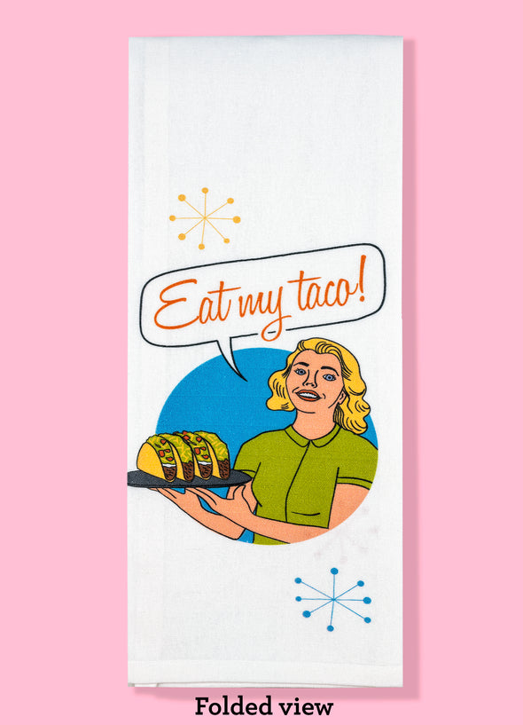 Folded dishtowel with an illustration of a woman holding a plate of tacos and the text Eat My Taco.