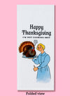 The folded view of the "Happy Thanksgiving I'm not cooking shit" tea towel. It features an illustrated woman holding a thumbs up and in her other hand a plate with a live turkey that is saying "hey y'all"