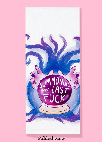 Folded view of Bad Grandma Designs dishtowel featuring manicured hands hovering over a crystal ball that says SUMMONING MY LAST FUCK.