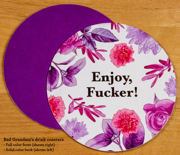 The front and back of the round drink coaster. The front features the text Enjoy, Fucker! in black font on a white background, surrounded with illustrations of flowers and leaves, stylized in purple and pink. The back is solid purple. 