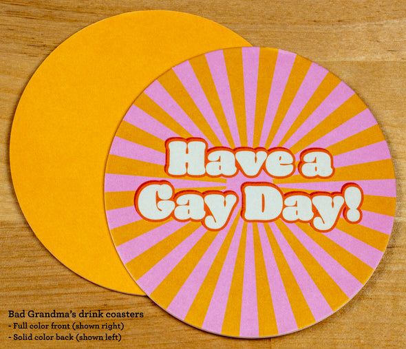 The front and back of the round drink coaster. The front features the text Have a Gay Day in 1970s font with a background of a pink and yellow sunburst. The back is solid yellow. 