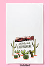 Unfolded dishtowel with the phrase Arizona, Prickly Shit Everywheres an illustration of cacti including saguaro, barrel cactus, and prickly pear.