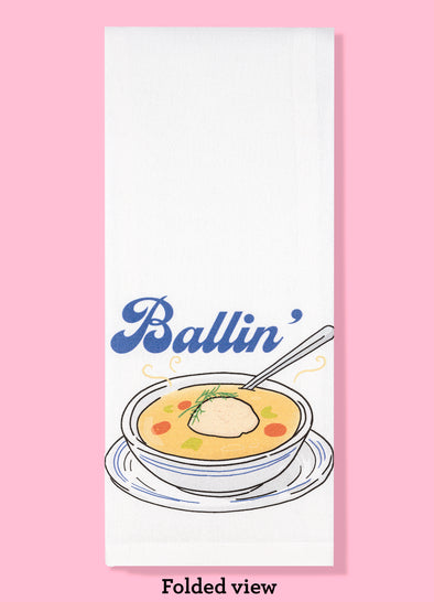 Folded dishtowel with illustration of matzo ball soup and the text Ballin.