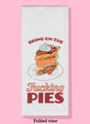 Folded dishtowel with the phrase Bring on the Fucking Pies with an illustration of a stack of three slices of pie.