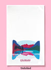 Unfolded dishtowel with an illustration of a lakeside landscape and the phrase Colorado Holy Shit, Its Fantastic Here.