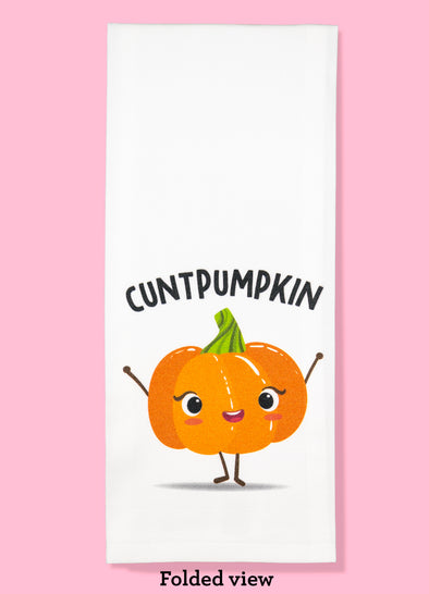 Folded dishtowel with an illustration of a smiling pumpkin and the phrase Cunt Pumpkin.