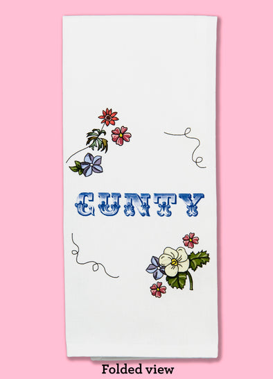 Folded dishtowel with floral illustrations and the phrase Cunty in decorative type.