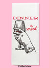 Folded dishtowel with an illustration of a hand holding a glass of red wine and the phrase Dinner is Served.