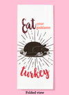 Folded dishtowel with an illustration of a cooked turkey and the phrase Eat Your Goddamn Turkey.