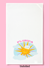 Unfolded dishtowel with the phrase Florida, Fuck Me Its Humid and an illustration of a sweating sun and clouds.