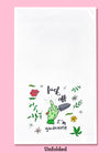 Unfolded dishtowel with an illustration of a gardening glove with the middle finger extended, a garden spade, and floral motifs with the phrase Fuck Off I'm Gardening.