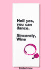 Folded dishtowel with an illustration of a red wine stain and the phrase Hell Yes You Can Dance Sincerely Wine.