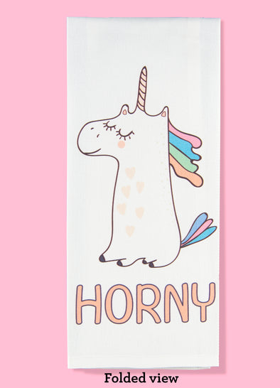 Folded dishtowel with an illustration of a smug unicorn and the phrase Horny.