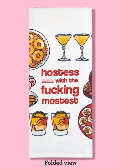 Folded dishtowel with illustrations of 1970s era foods and the phrase Hostess with the Fucking Mostest.