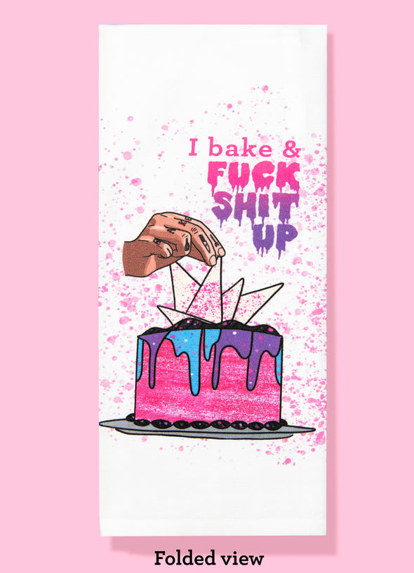 Folded dishtowel with an illustration of a tattooed hand decorating a cake and the words I Bake and Fuck Shit Up.