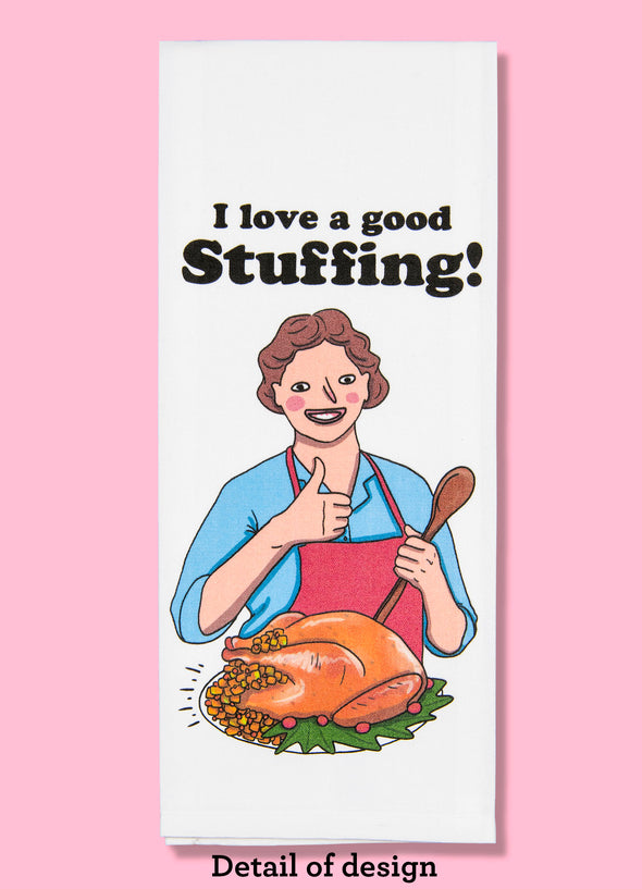 Folded dishtowel with an illustration of a smiling person giving the thumbs up gesture in front of a cooked turkey overflowing with stuffing. Above the illustration is the phrase I Love a Good Stuffing.