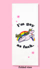 Folded dishtowel with an illustration of a unicorn leaping in front of a rainbow and the phrase I'm Gay as Fuck.