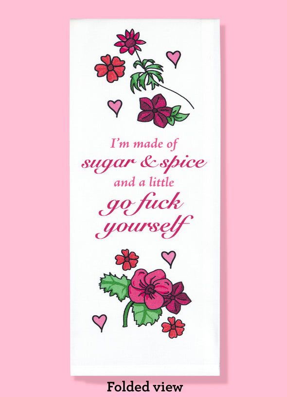 Folded dishtowel with the phrase I'm made of sugar and spice and a little go fuck yourself. Above and below the phrase are illustrations of cartoon flowers and hearts