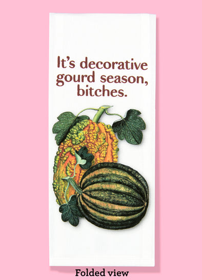 Folded dishtowel with an illustration of vintage gourds and the phrase It's Decorative Gourd Season Bitches.
