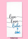 Folded dishtowel with an illustration of a drop of liquid and the phrase Live Love Lube.