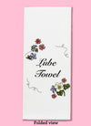 Folded dishtowel with floral illustrations and the phrase Lube Towel.