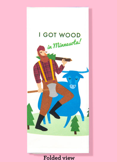 Folded dishtowel with an illustration of Paul Bunyan and Babe the Blue Ox. Bunyan has a tree slung over his shoulder. Above him is the phrase I Got Wood in Minnesota.
