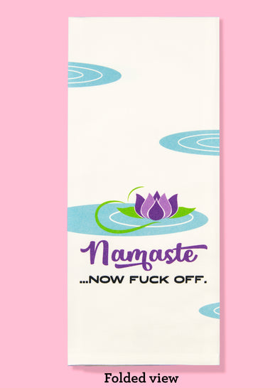 Folded dishtowel with the phrase namsate now fuck off. The illustration is of a purple lotus flower in a puddle