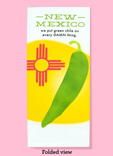 Folded dishtowel with the phrase New Mexico we put green chile on every DAMN thing. The illustration is of a large green chile and a red Zia symbol against a yellow oval background