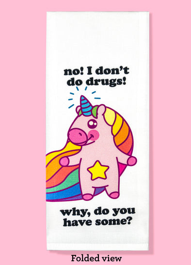 Folded dishtowel with the phrase No I don't do drugs why do you have some? The illustration is of a cartoon unicorn smiling, with a rainbow mane and a star on its belly