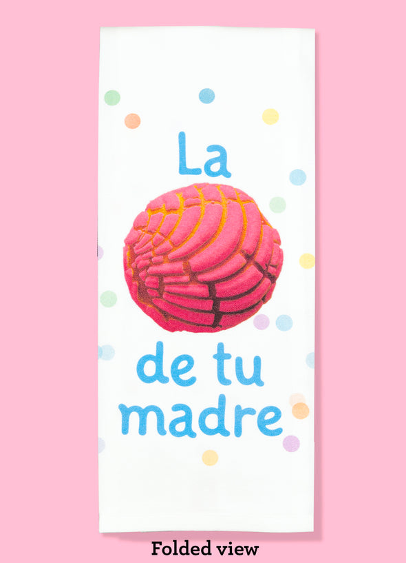 Folded dishtowel with an illustration of concha bread and the Spanish phrase La Concha de tu Madre.