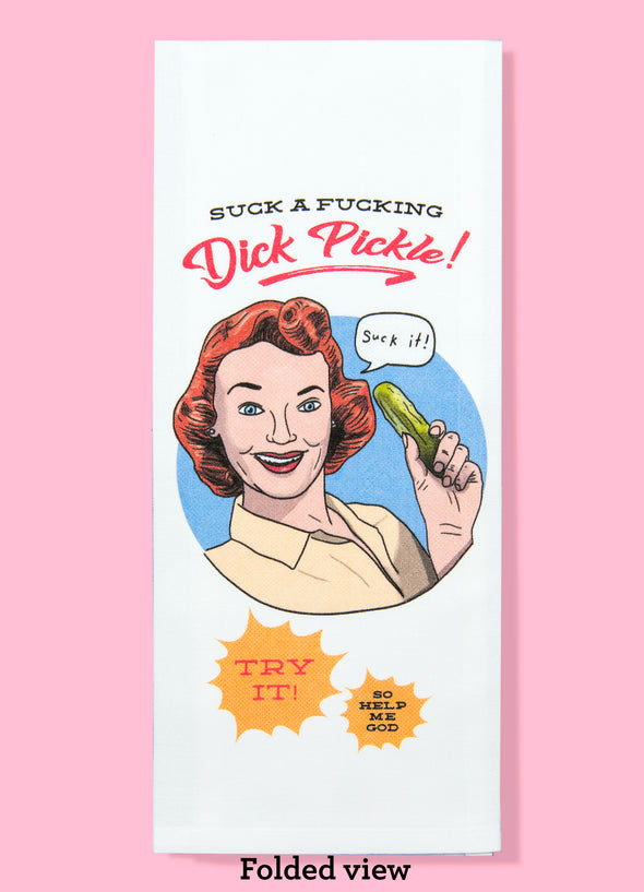 Folded dishtowel with the phrase suck a fucking dick pickle. The illustration is of a cartoon woman holding up a pickle and saying in a speech bubble suck it. Below the illustration are two starbursts: the first says try it; the second says so help me god