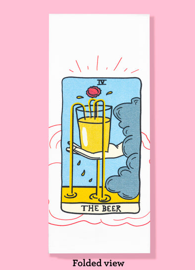 Folded dishtowel of an illustration of a faux tarot card featuring a hand emerging from a dark cloud holding an overflowing beer glass with the phrase The Beer