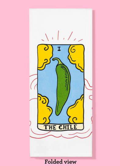 Folded dishtowel of an illustration of a faux tarot card featuring a green chile surrounded by 4 clouds with the phrase The Chile