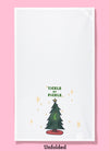 Unfolded dishtowel of an illustration of a Christmas tree with a large pickle ornament with the phrase tickle my pickle
