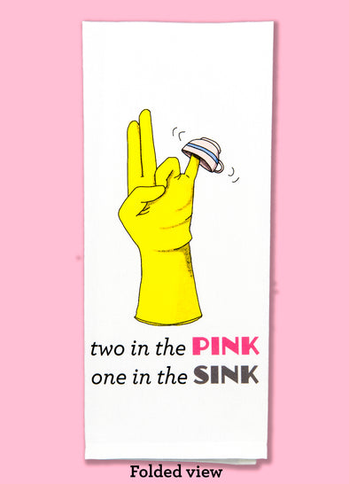 Folded view of the two in the pink, one in the sink dishtowel. This dishtowel features a rubber glove with index and and middle finger together and extended, the ring finger and thumb touching, and the pinky extended to the side with a tea cup on it, as well as the humorous phrase.