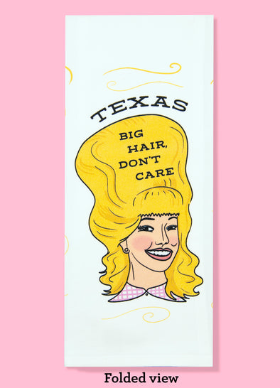  Folded dishtowel with the phrase Texas big hair, don't care. The illustration is of a cartoon smiling woman with large blonde hair.