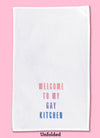 Unfolded dishtowel with the phrase welcome to my gay kitchen. The text fades from a peach color to blue.